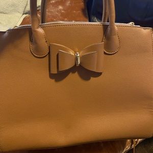 Tan handbag with bow and gold tone hardware detail.